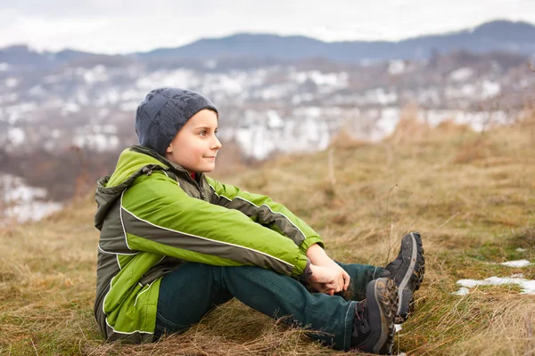 Χαριτωμένο Αγόρι Κάθεται Στο Γρασίδι Ένα Εξοχικό Περιβάλλον — Φωτογραφία Αρχείου