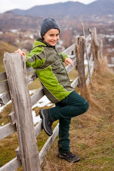 Kid sitting on wooden fence — Stock Photo, Image