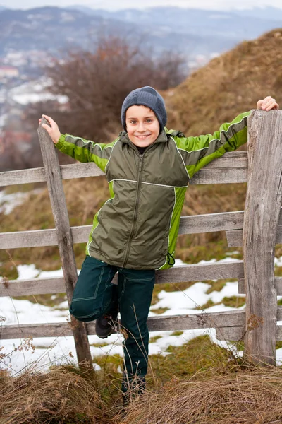 Niño sentado en una valla de madera —  Fotos de Stock