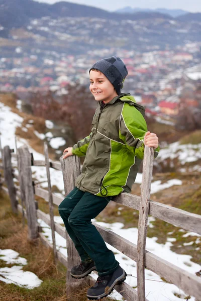 Kid zittend op houten hek — Stockfoto
