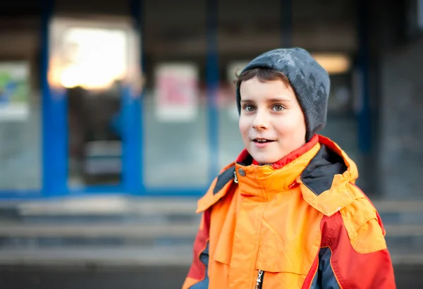 Хлопчик в помаранчевому пальто в міському середовищі — стокове фото