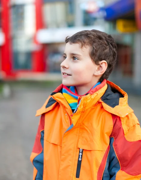 Jongen in oranje jas in stedelijke omgeving — Stockfoto