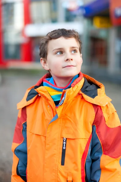 Vértes Portré Egy Szép Gyermek Narancssárga Téli Kabát Városi Környezetben — Stock Fotó
