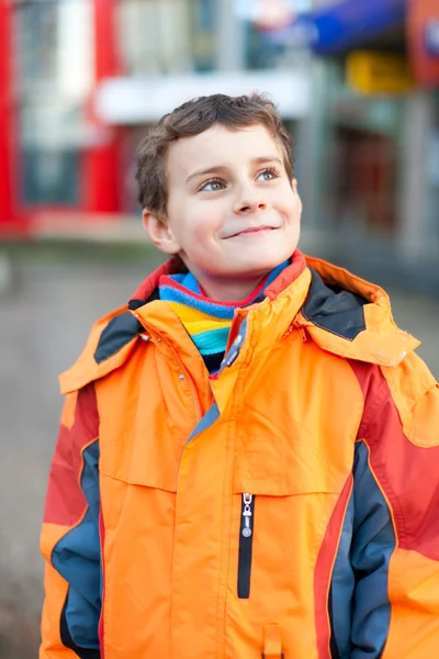 Fiú, a narancssárga kabátot a városi környezetben — Stock Fotó