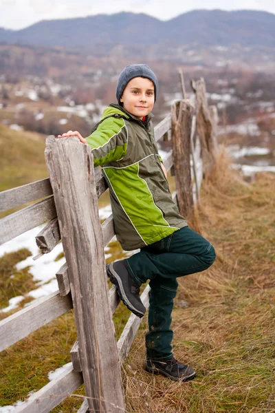 Enfant assis sur une clôture en bois Photos De Stock Libres De Droits