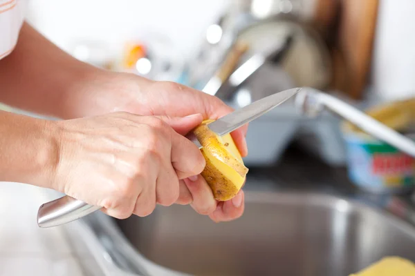女性の手は台所で剥離ジャガイモ — ストック写真