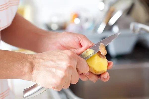 女性の手は台所で剥離ジャガイモ — ストック写真