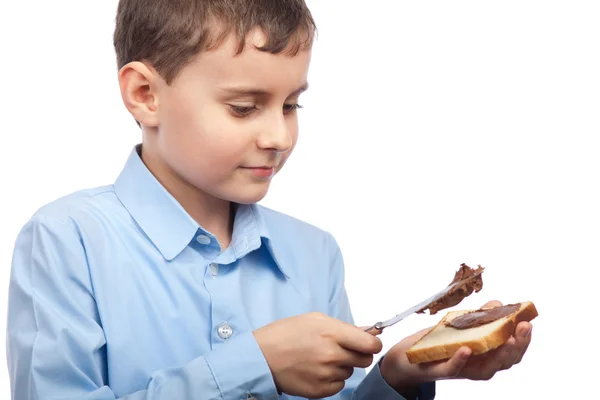 Niño extendiendo mantequilla de maní o chocolate sobre el pan — Foto de Stock