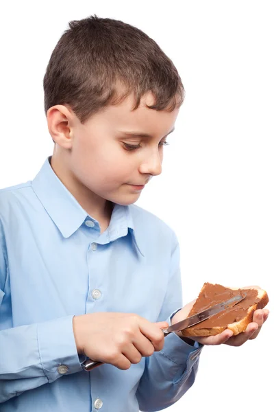Criança espalhando manteiga de amendoim ou chocolate no pão — Fotografia de Stock