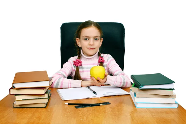 Girl with an apple being at a writing table with books — Stock Photo, Image