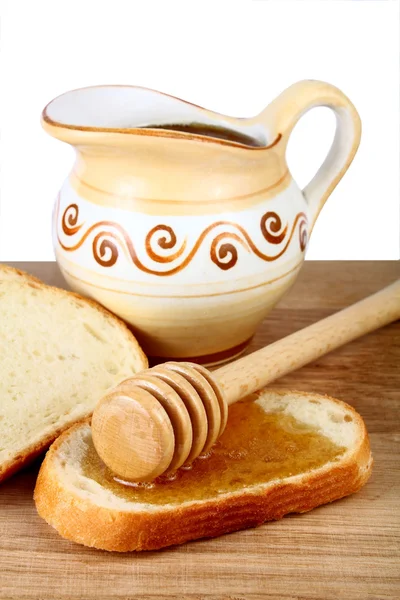 Miel en una jarra y pan a bordo — Foto de Stock