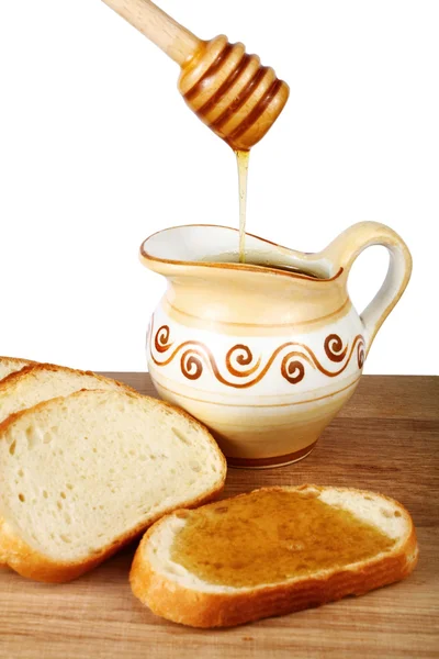 Honing in een kruik en brood aan boord — Stockfoto