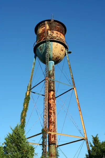 Velha torre de água enferrujada contra o céu azul — Fotografia de Stock