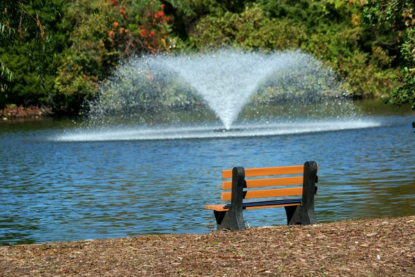 Fountain on a pond with bench — Stock Photo, Image
