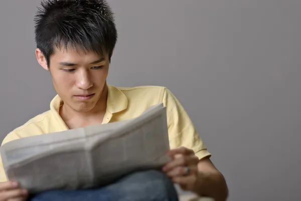 Azjatycki człowiek młody czytanie gazety — Zdjęcie stockowe