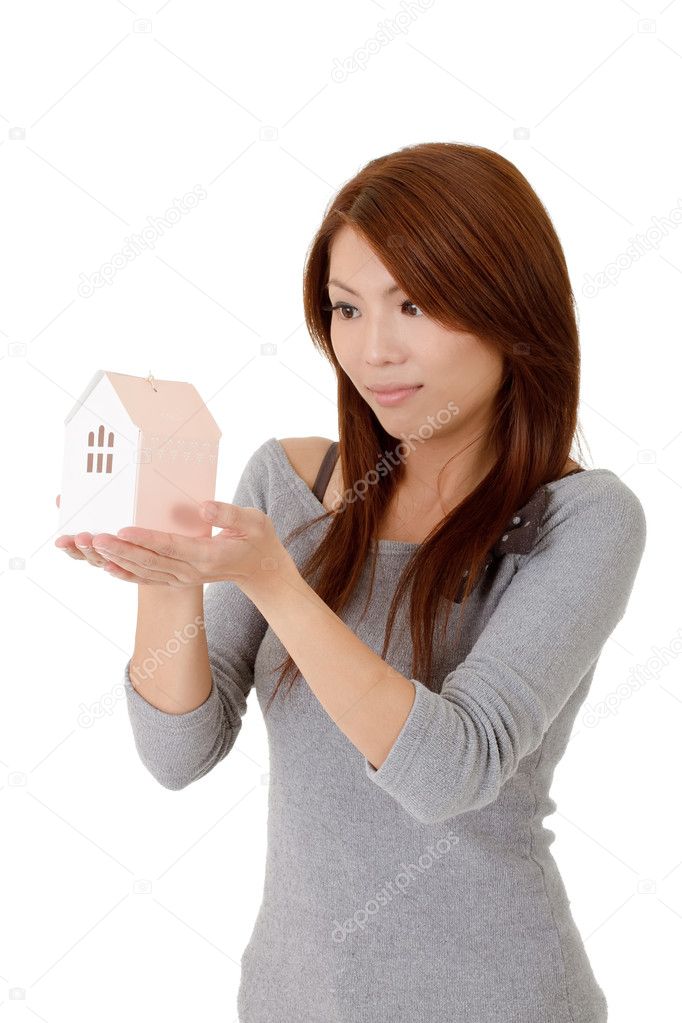 Woman holding house model on hand and looking against white background.