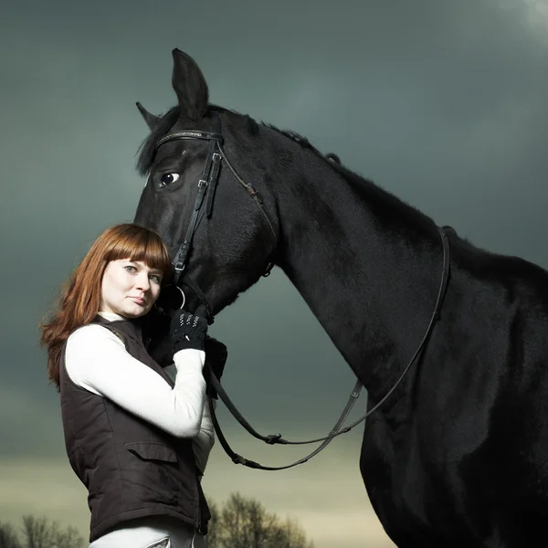 Belle jeune femme avec un cheval noir — Photo