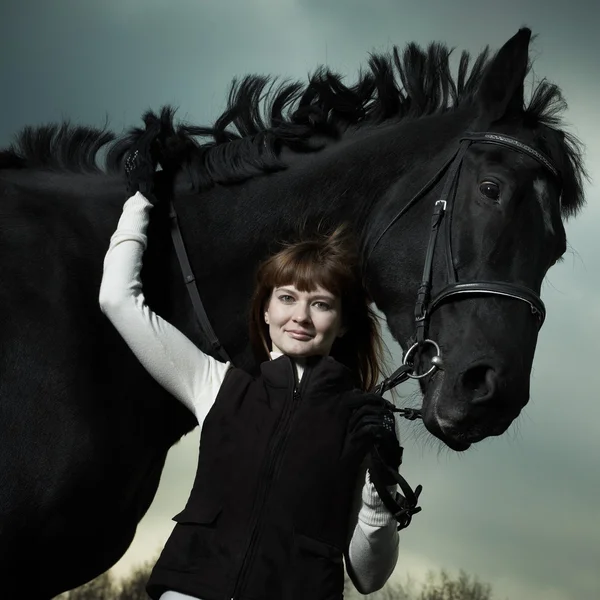 Mulher bonita com um cavalo preto — Fotografia de Stock
