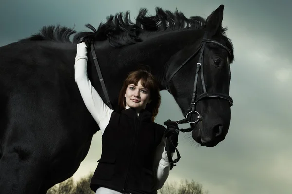 Красива молода жінка з чорним конем — стокове фото