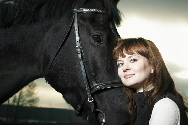 Mulher bonita com um cavalo preto — Fotografia de Stock