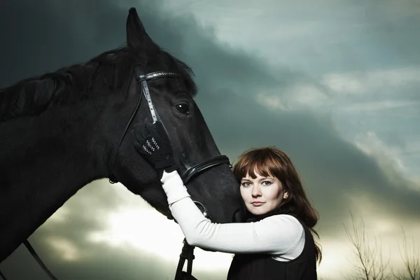 Bella giovane donna con un cavallo nero — Foto Stock