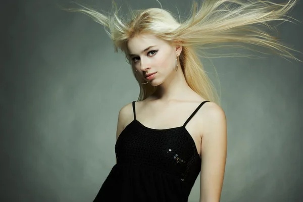 Fashion portrait of the young blonde woman with flying hair — Stock Photo, Image