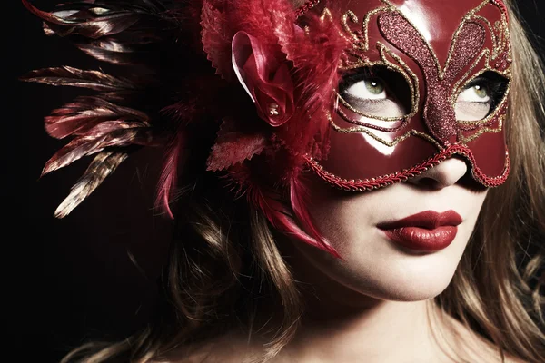 Schöne junge Frau in einer roten geheimnisvollen Maske — Stockfoto