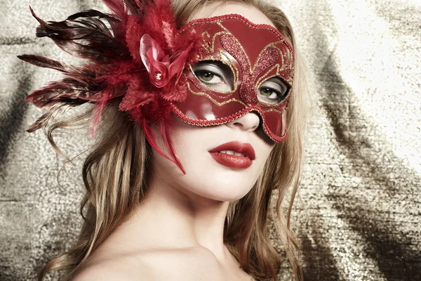 Belle jeune femme dans un masque vénitien mystérieux rouge sur un fond doré — Photo
