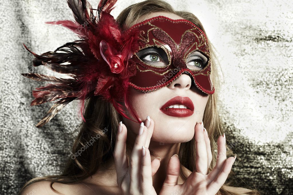 Beautiful young woman in a red mysterious venetian mask on a gold backgroun