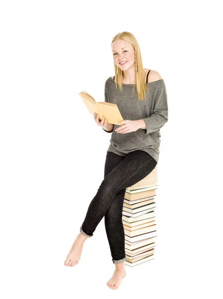 Jong meisje, zittend op een stapel boeken — Stockfoto