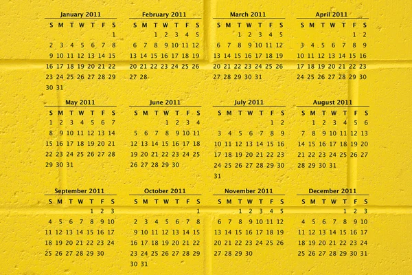 2011 kalendář na pozadí žluté cihlové zdi — Stock fotografie