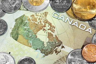 Close up of a one hundred canadian dollar bill showing the map of Canada, surrounded by loony and tuney coins. clipart