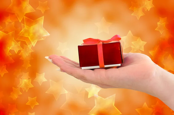 Female hand holding red gift on starry background — Stock Photo, Image