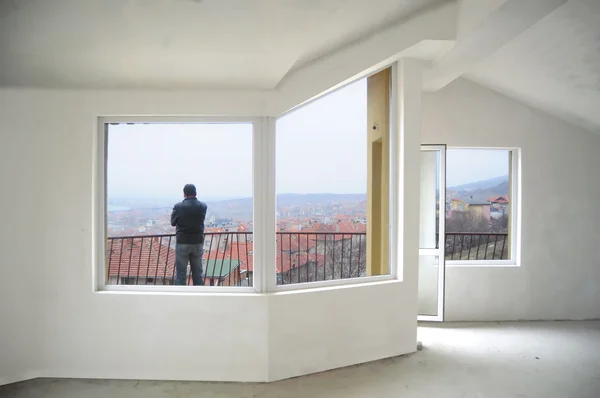 Молодой человек смотрит со своего нового балкона — стоковое фото
