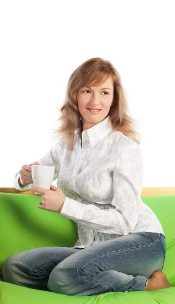 Uśmiechający Się Blond Kobieta Kanapie Posiada Filiżankę Kawy Ogląda Telewizję — Zdjęcie stockowe