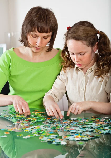 Lány és anya csinál puzzle — Stock Fotó
