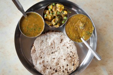 Traditional Indian cuisine vegetarian thali served in small bowls on a round tray. clipart