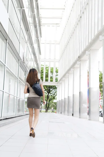 事務所ビルを渡し通りの上を歩いてアジア女性実業家の背面図 — ストック写真