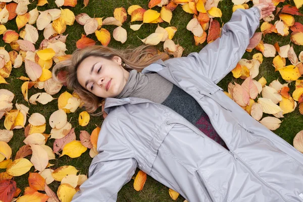 Menina bonita repousa sobre folha de outono — Fotografia de Stock