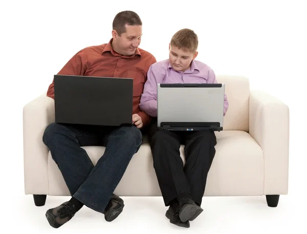父亲和儿子坐在沙发上使用便携式计算机 — 图库照片