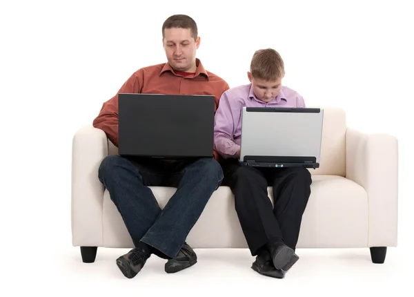 父亲和儿子坐在沙发上使用便携式计算机 — 图库照片
