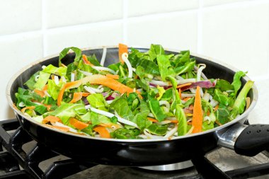 Preparing of fresh vegetarian green meal in pan clipart