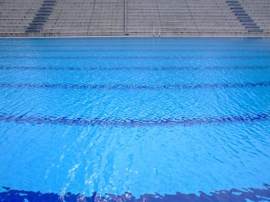 Trembling surface of an Olympic size swimming pool in empty sport arena clipart