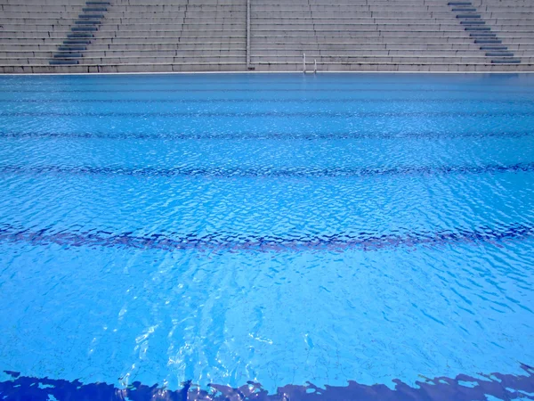 空のスポーツ アリーナでオリンピック サイズのスイミング プールの震えている表面 — ストック写真
