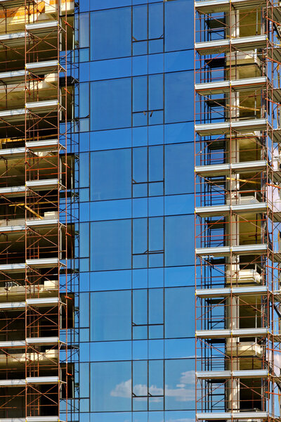 Scaffoldings at building with blue windows during construction