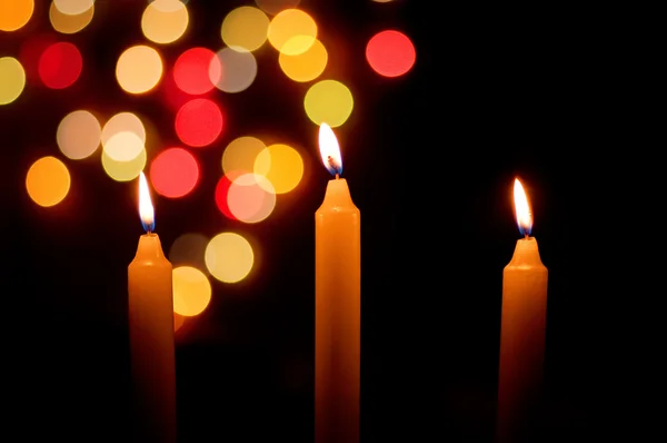 Velas encendidas con luces navideñas desenfocadas detrás — Foto de Stock