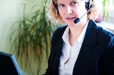 Closeup of a business woman using a laptop and talking into headset clipart