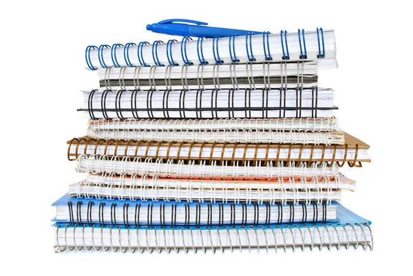 Stapel spiraal-laptops geïsoleerd op wit met een blauwe pen op de top Stockfoto