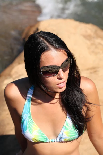 Young woman on riverbank sunglasses and bikini top — Stock Photo, Image