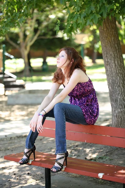 Jovem caucasiano adolescente menina sentado no banco do parque — Fotografia de Stock